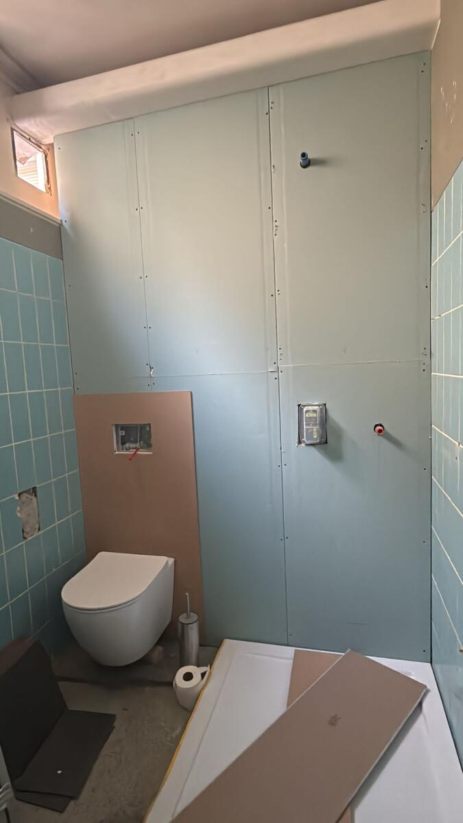 Badkamer voor - blauwe tegels en leidingwerk